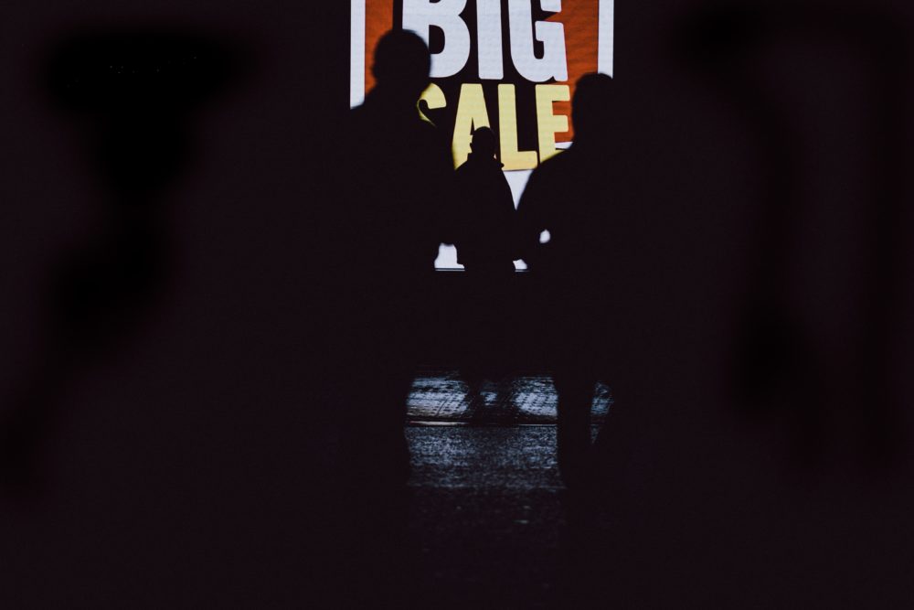 silhouette of people in front of a big sale sign