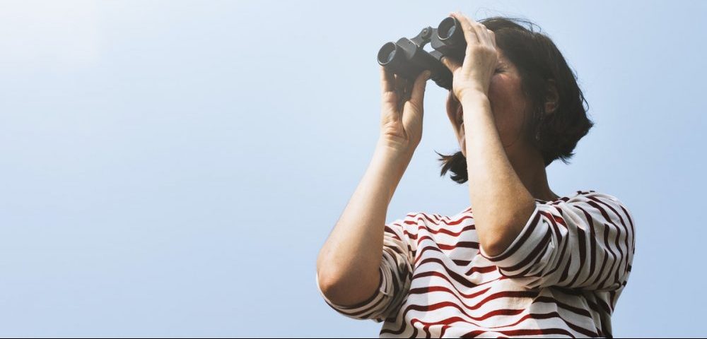 woman searching with binoculars outside