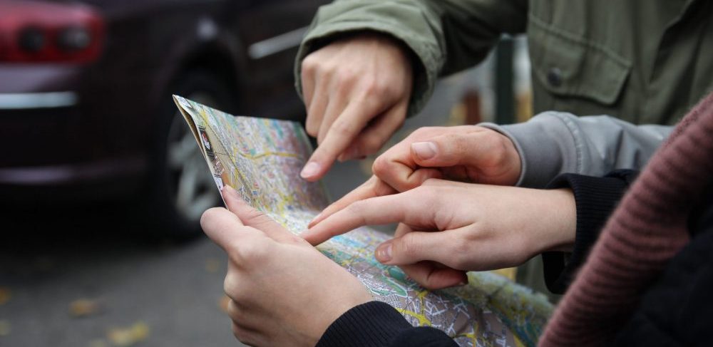 three people's hands pointing at a map