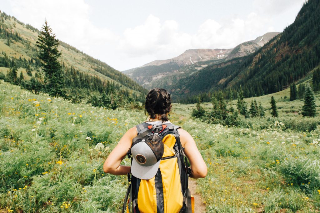 person hiking down an outdoor path with a hat and backpack