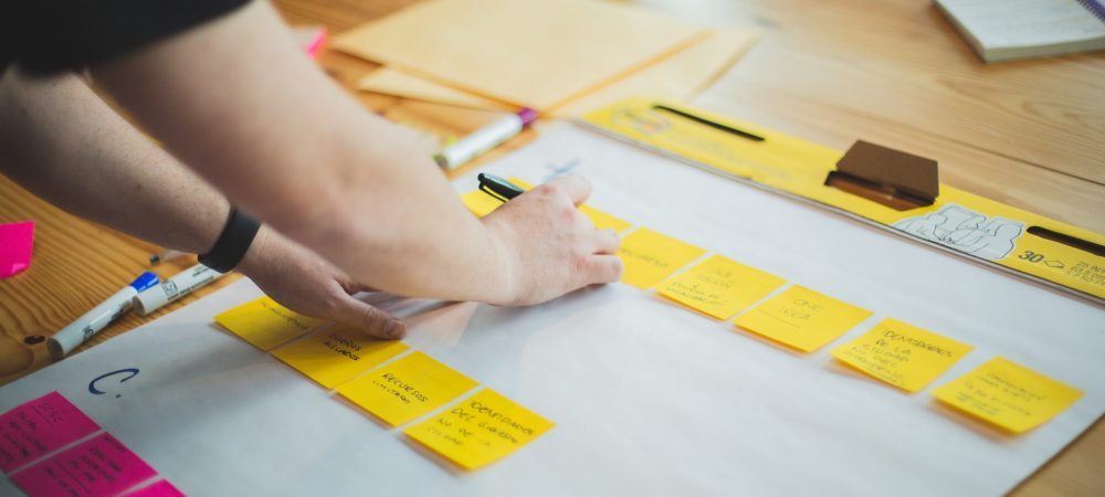 person writing out a strategy on a sticky note
