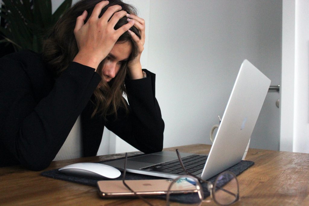 woman at computer frustrated holding her head in her hands