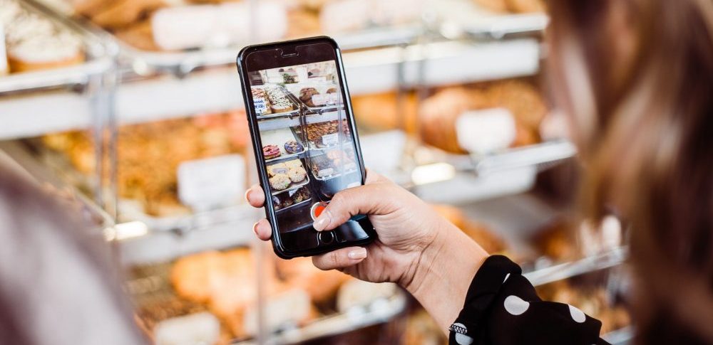 woman taking a photo of baked goods with a smartphone