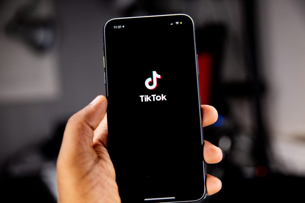 person holding a smartphone with tiktok homepage pulled up