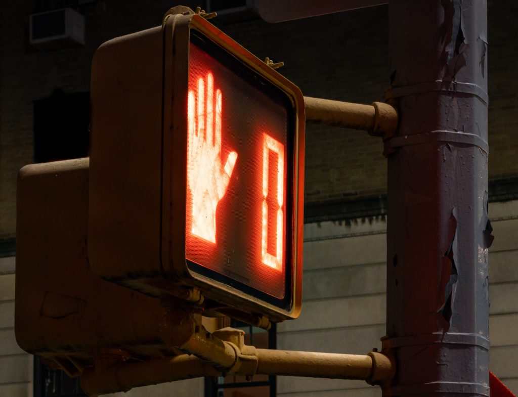 crosswalk sign with a zero and a hand lit up