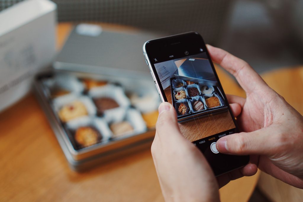 person taking photo of pastries on smartphone for F&B paid social