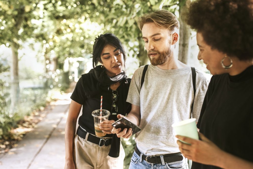 three people on the sidewalk looking at navigation on a smartphone