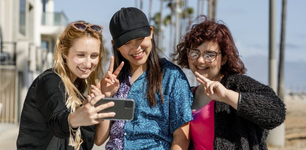 Teen girls taking selfie, enjoying summer together in Venice Beach, Los Angeles