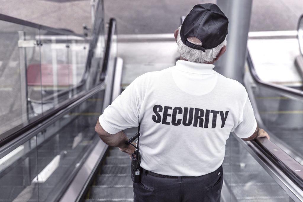 Back of a security guard on escalator.