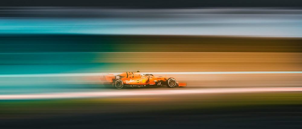 orange car zooming by on a racetrack