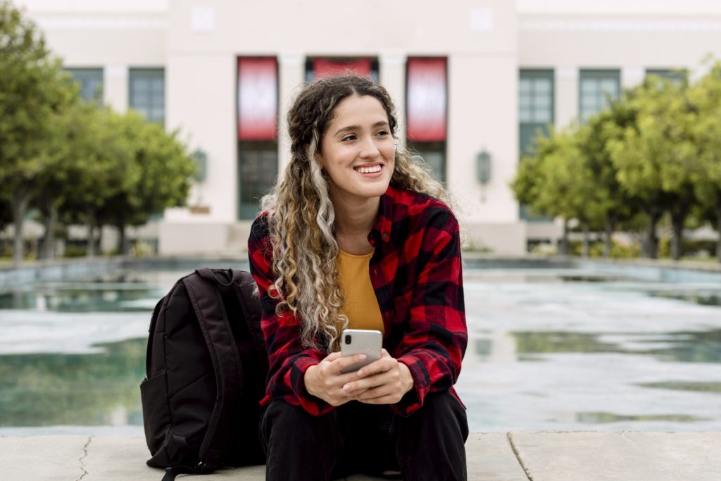 girl sitting outside on her smartphone