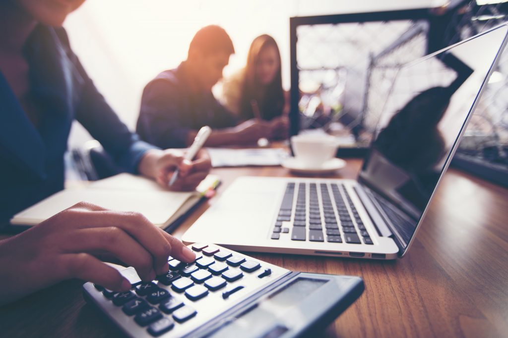 The hands of a female accountant are using a calculator to calculate taxes. 