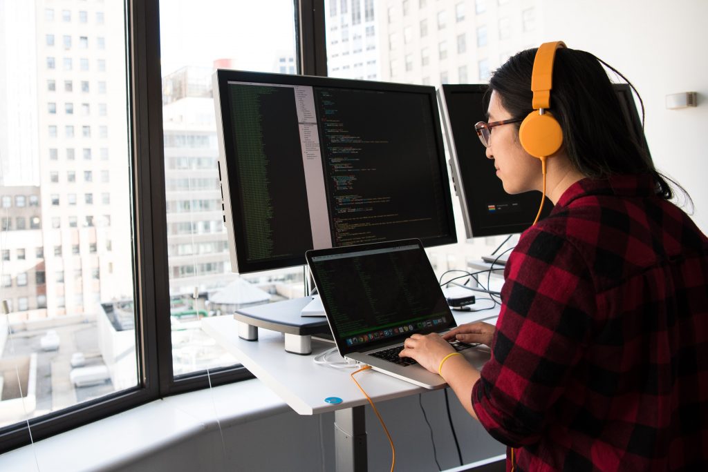 girl wearing orange headphones working on a desktop computer