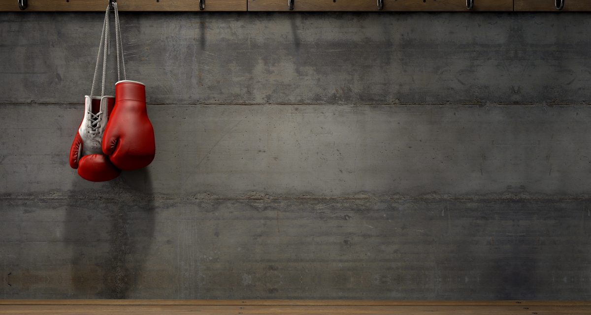 Spotlit boxing gloves hanging on a hanger above an empty wooden bench in a locker change room - 3D render