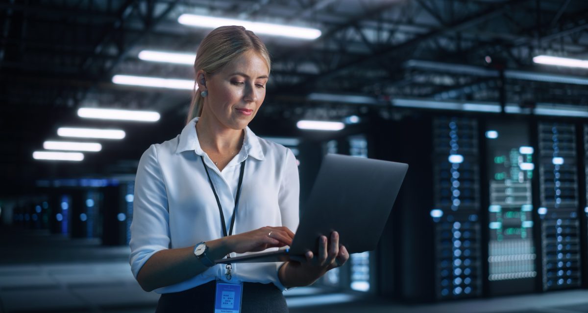 Portrait of Successful Female Chief Engineer or CEO Using Laptop Computer to Optimise Server Farm Cloud Computing Facility at the Evening Office. Cyber Security, Network Protection Concept