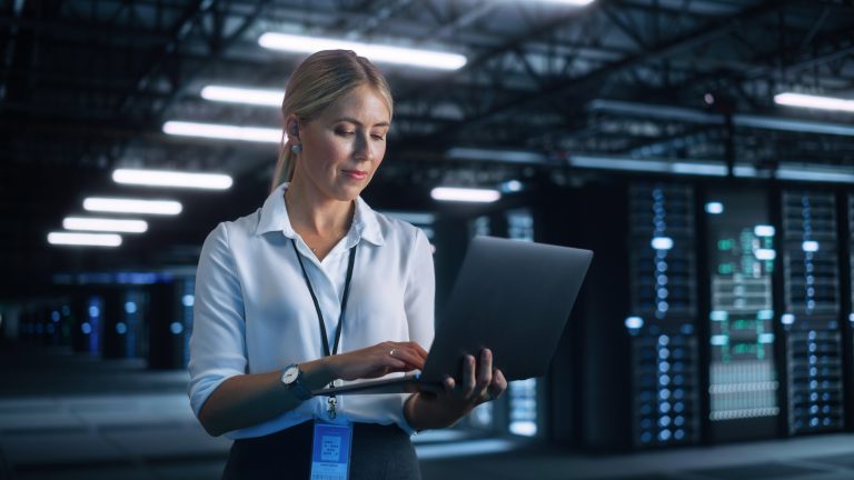 Portrait of Successful Female Chief Engineer or CEO Using Laptop Computer to Optimise Server Farm Cloud Computing Facility at the Evening Office. Cyber Security, Network Protection Concept