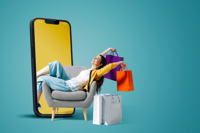 Happy fashionable young woman sitting and holding shopping bags in a smartphone, she is doing online shopping, blank copy space